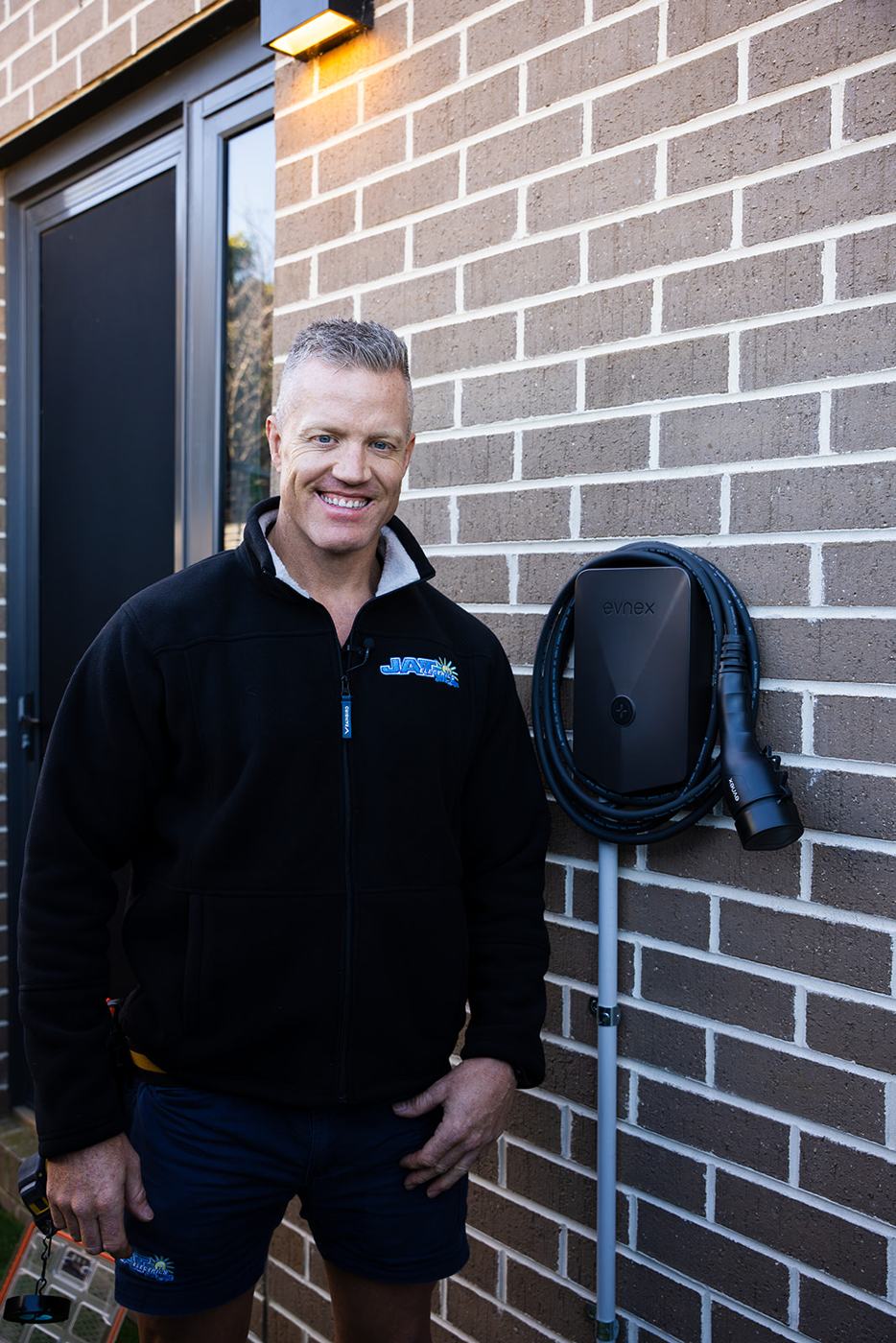 Lance from JAT Electrics smiling beside an installed EV charger