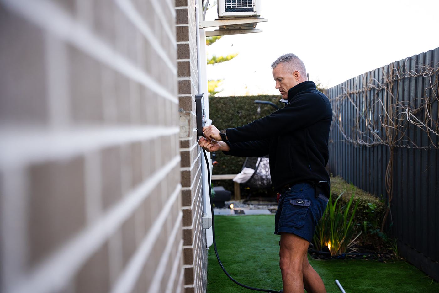 Electrician installing an EV charger on a brick wall