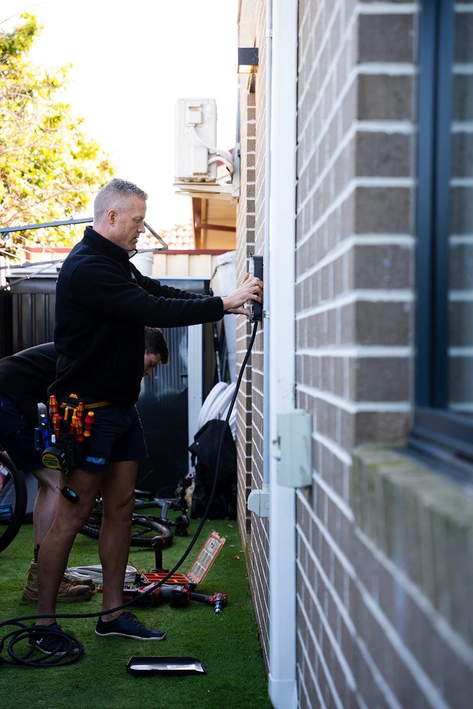 Electrician installing an EV charger beside a house