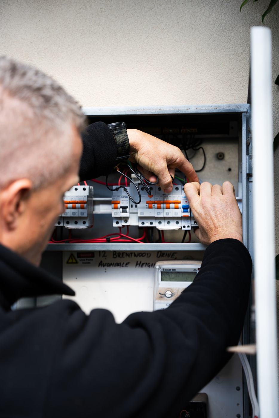 Electrician working inside an open switchboard